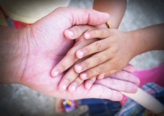 adult hand holding child hands