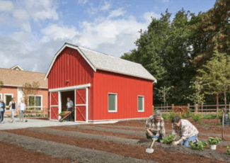 older people gardening in front of red barn